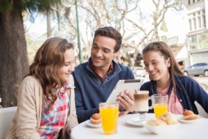 Dad enjoying breakfast with two daughters on streetside patio
