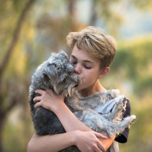 Boy kissing and holding dog
