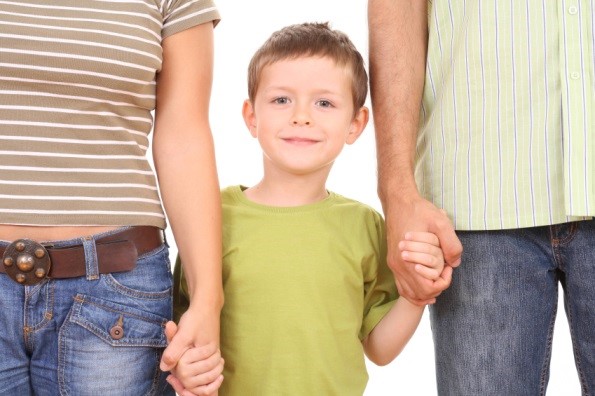 Child smiling holding hands of parents