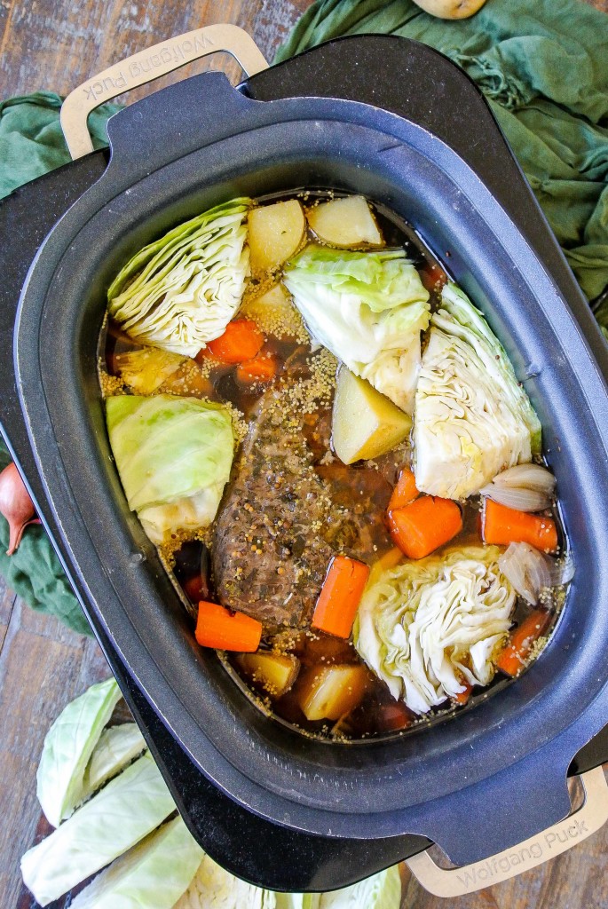 Cabbage being added to corned beef, potatoes and carrots