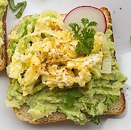 Whole grain toast topped with smashed avocado, hard boiled egg and a slice of radish