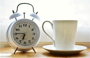 Alarm clock set for 6:45 am and a coffee cup