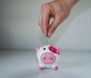 hand placing coin into piggy bank