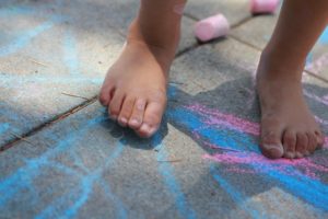 Kids playing with sidewalk chalk, young person playing on chalk