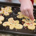 child adding sprinkles to gingerbread people