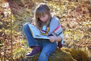 child reading a book outside