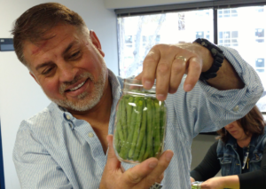 Man holding jar of green beans being prepared for canning