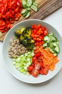 bowl with whole grain, broccoli, red peppers, cucumbers, carrots, tomatoes and celery