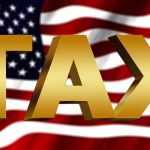 the word tax In front of an American flag