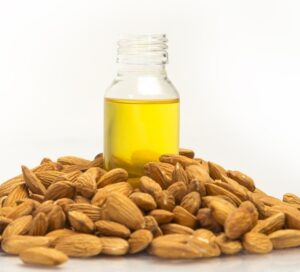 bottle of oil surrounded by almond nuts