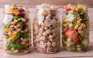 Three jars filled with a variety of bean salads.