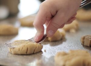 child's hand shaping cookies