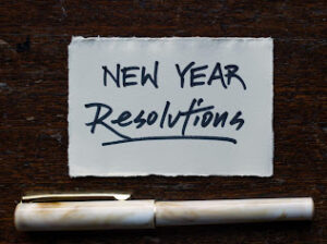 Post It Note stating "New Year Resolutions" with a pen below