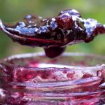 Spoon full of berry jam and a jar of jam