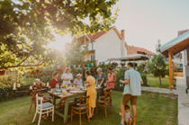 Group of people gathered around a large table of food in a backyard