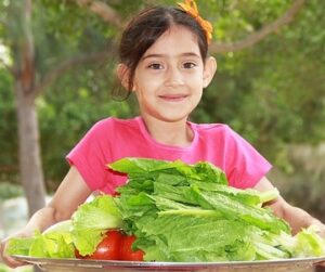 Young girl with a pile of salad greens