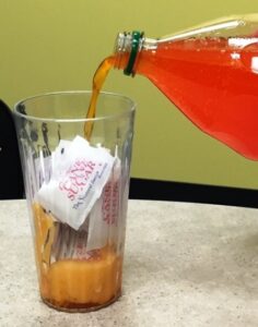 Orange Soda being poured over sugar packets