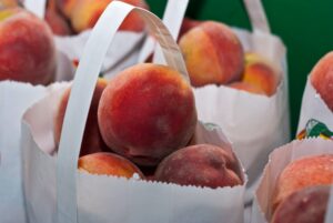 Peaches in a white bag to purchase at a farmers market