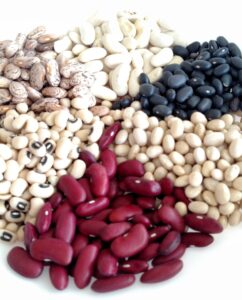 A plate of 6 variety of dry beans, including kidney, black eyed peas, pinto, great northern, black and small white beans.
