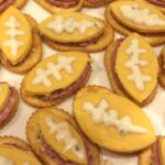Oval (football) shaped appetizers made with a cracker, topped with luncheon meat and a slice of cheese then decorated with cream cheese to look like the laces on a football.