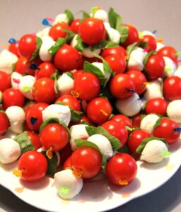Small balls of cheese, tomatoes and basil leaves threaded on a skewer.