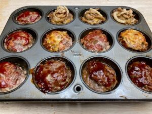 Cooked muffin pan meat loafs- 12 in the pan with different toppings.