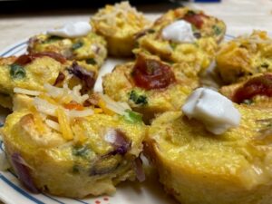 Egg and vegetable bites made in a standard muffin pan. Some topped with salsa, other with sour cream or shredded cheese.