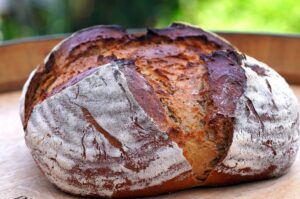 Artisan bread loaf that is round "boule" in shape with a cross cut split that happened during baking.