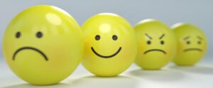 Four yellow balls with four different emotions: frown, smile anger and worry on them