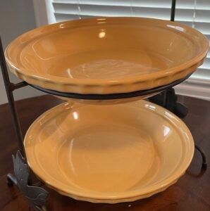 Two yellow porcelain pie plates in a display holder