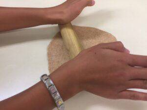 person rolling out dough for a flat bread