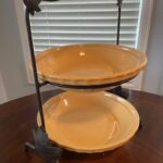 Two yellow pie plates displayed in a rod iron pie holder