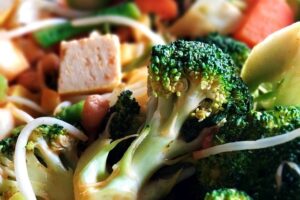 Fry pan of broccoli , carrots, celery, cubed tofu and other vegetables.