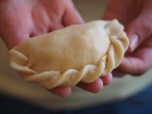 Empanada filled in raw dough ready to go on baking sheet