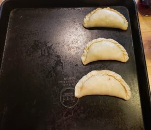 Empanadas laid out on a baking sheet