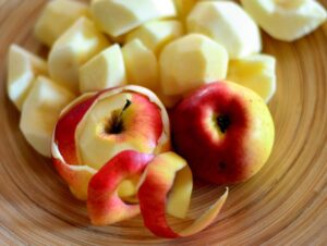 Raw apples being peeled and cut into pieces.