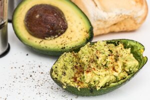 Avocado cut in half lengthwise with one half filled with mashed and seasoned avocado flesh.