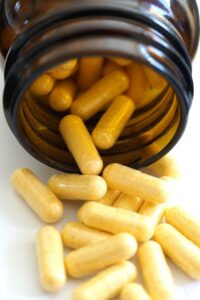 Brown medicine bottle on its side, with fiber capsules tumbling out of it.