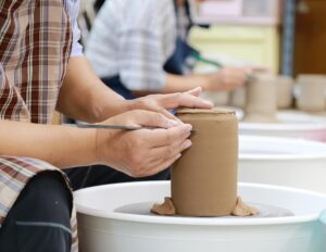 Two people sitting at pottery wheels while shaping clay