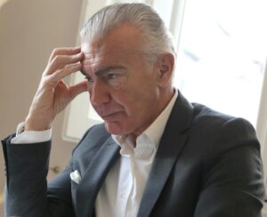 Older gentlemen holding his head resembling having a headache while concentrating on work