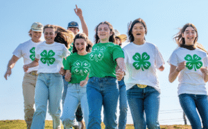Several youth running with green and white t-shirts with the 4-H logo on front.