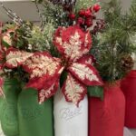 Jars that are recycled and painted green, white and red that have artificial poinsettia, berries, and pine boughs put inside the jars to create a centerpiece